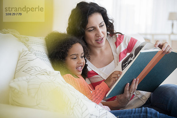 Mutter und Tochter lesen auf dem Sofa