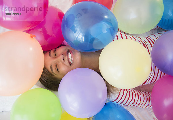 Gemischtrassige Frau spielt mit Luftballons