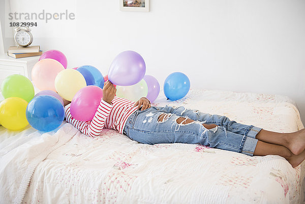 Gemischtrassige Frau spielt mit Luftballons