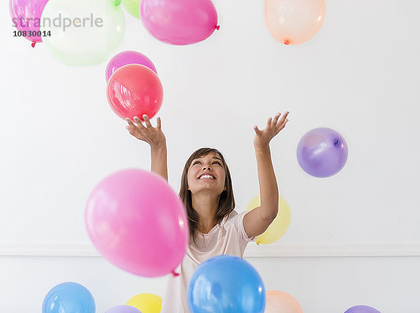 Gemischtrassige Frau spielt mit Luftballons