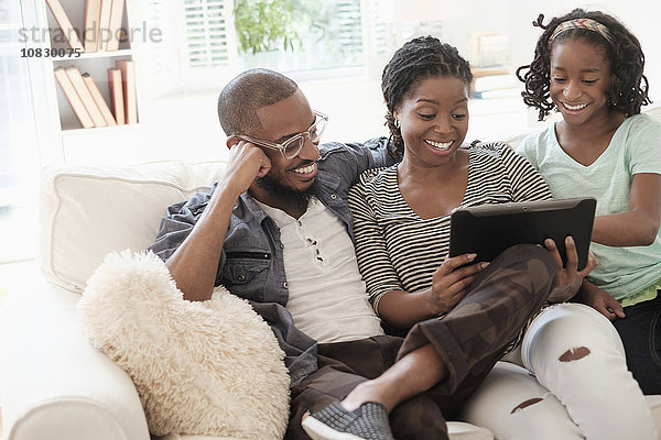 Schwarze Familie benutzt digitales Tablet auf dem Sofa