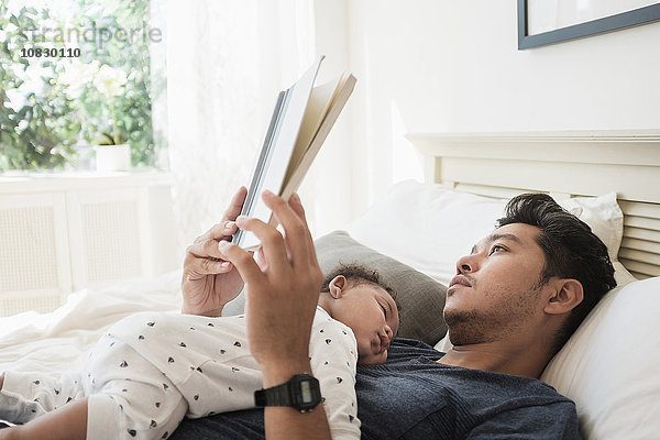 Vater liest mit schlafendem Babysohn