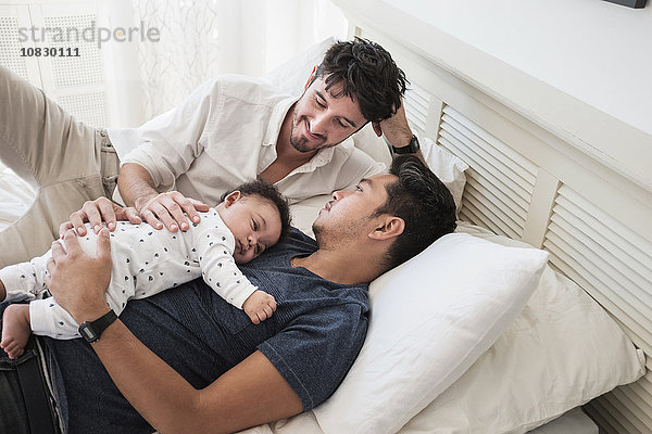 Schwule Väter entspannen sich mit ihrem kleinen Sohn im Bett