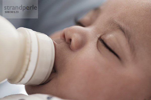 Nahaufnahme eines gemischtrassigen Jungen  der mit der Flasche gefüttert wird