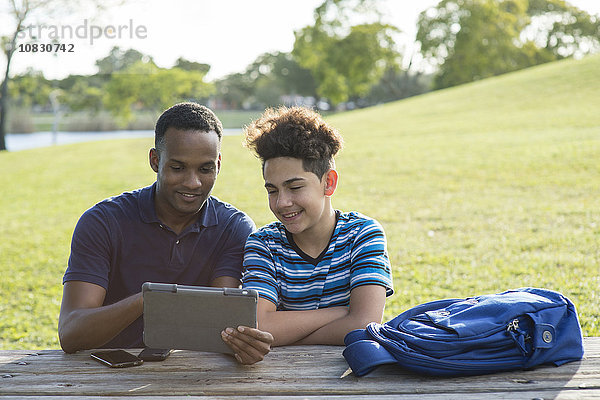 Vater und Sohn benutzen ein digitales Tablet im Park