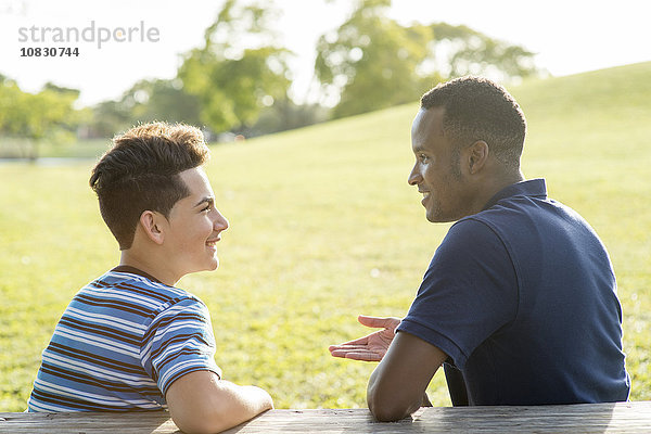 Vater und Sohn unterhalten sich am Tisch im Park