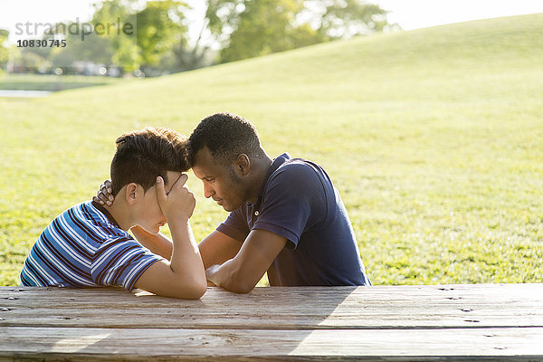 Vater und Sohn unterhalten sich am Tisch im Park