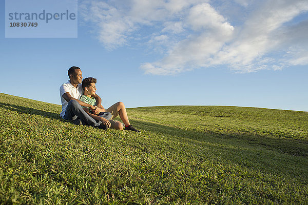 Vater und Sohn sitzen im Gras