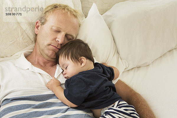 Vater und kleiner Sohn schlafen auf dem Bett