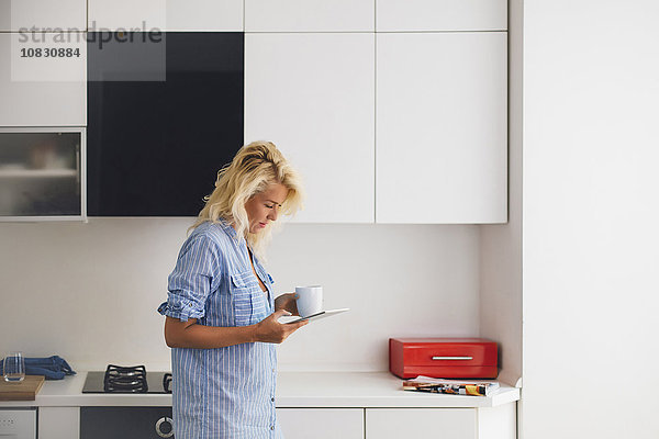 Frau benutzt digitales Tablet in der Küche