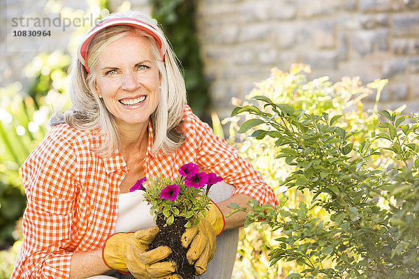 Kaukasische Frau pflanzt Blumen im Garten