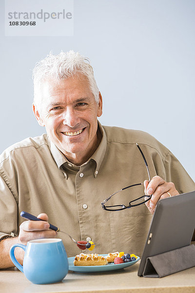 Kaukasischer Mann mit digitalem Tablet am Tisch