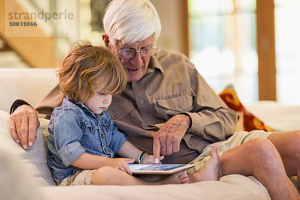 Kaukasischer Großvater und Enkel benutzen ein digitales Tablet