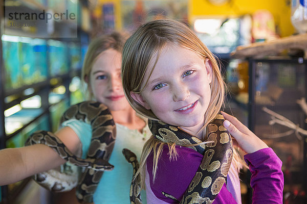 Kaukasische Mädchen spielen mit Schlangen in einer Zoohandlung