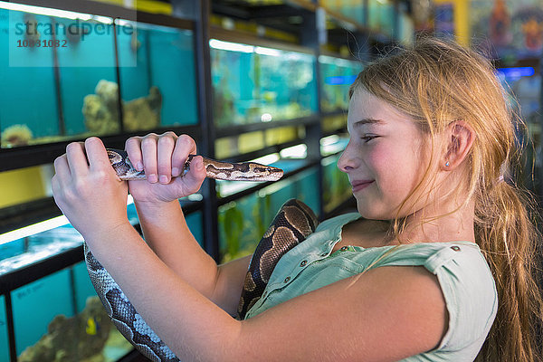 Kaukasisches Mädchen bewundert Schlange in Zoohandlung