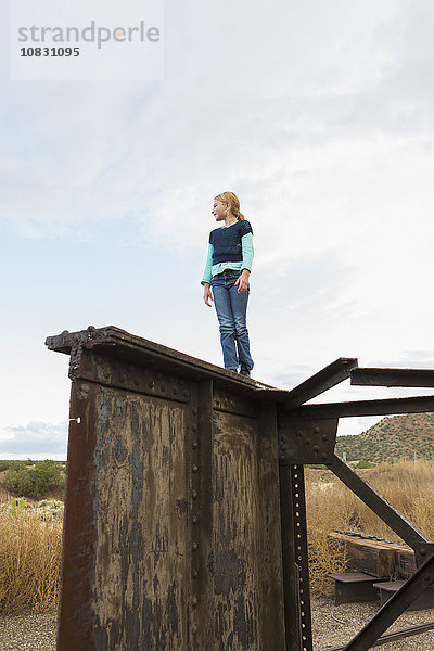 Kaukasisches Mädchen klettert auf rostige Struktur im Freien