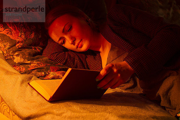 Kaukasische Frau liest Buch im Bett