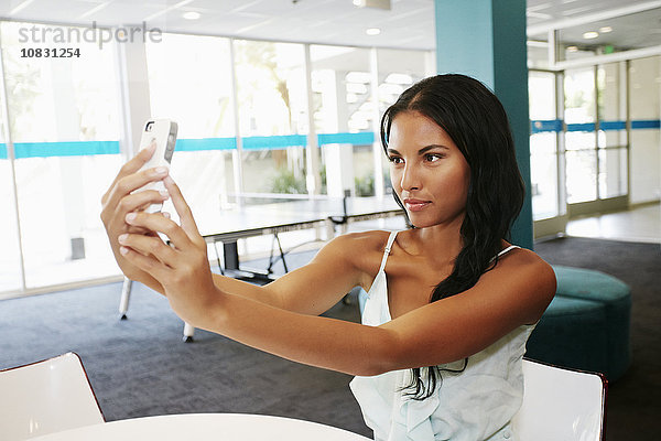 Gemischtrassige Frau macht Selfie am Tisch