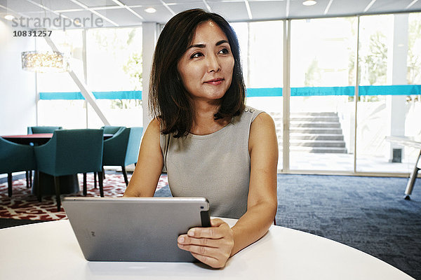 Japanische Geschäftsfrau benutzt digitales Tablet im Büro