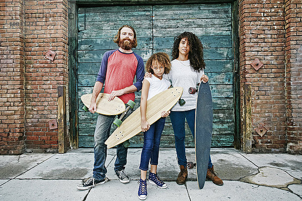 Familie hält Skateboards auf dem Bürgersteig