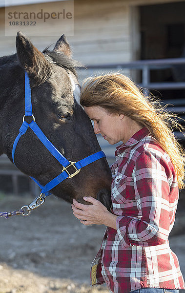 Kaukasische Frau umarmt Pferd auf Ranch