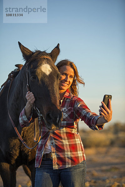 Kaukasische Frau nimmt Selfie mit Pferd