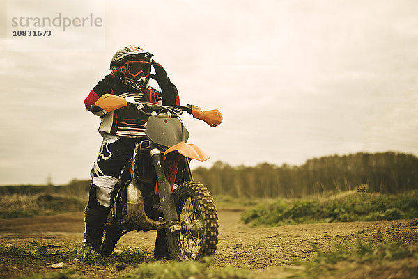 Kaukasischer Mann fährt Dirt Bike auf einem Feld