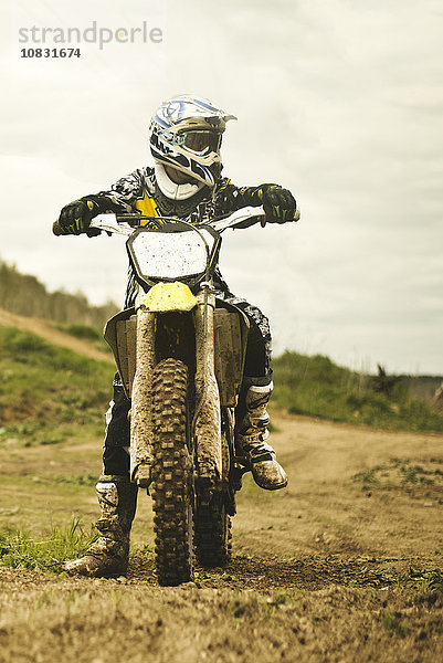 Kaukasischer Mann fährt Dirt Bike auf einem Feld