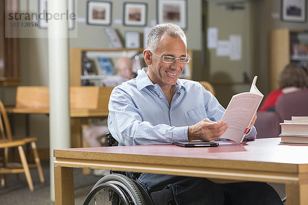 Kaukasischer Mann liest in einer Bibliothek