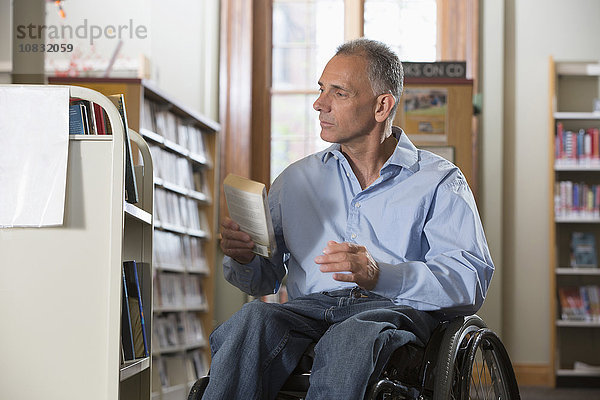 Kaukasischer Mann hält Buch in Bibliothek