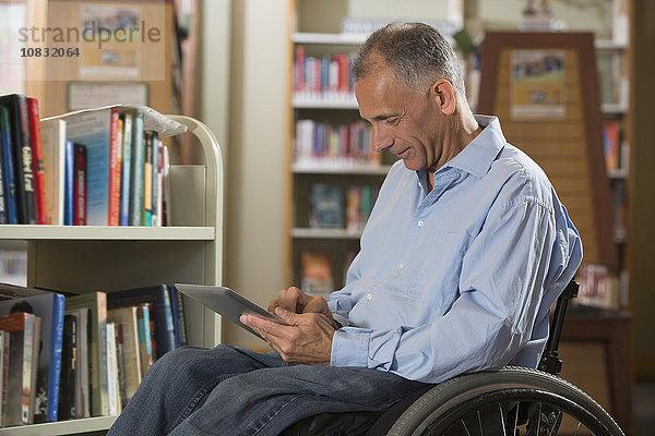 Kaukasischer Mann benutzt digitales Tablet in einer Bibliothek