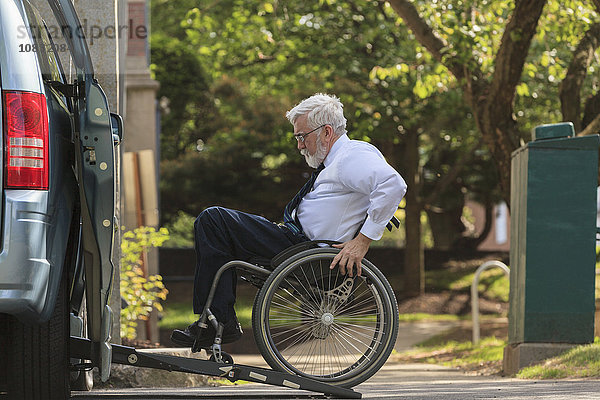 Kaukasischer Geschäftsmann im Rollstuhl steigt in einen Van ein