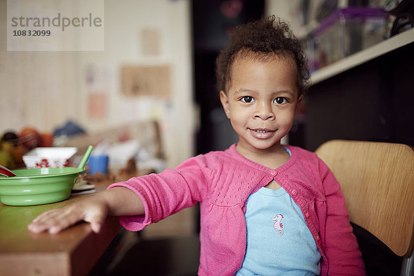 Gemischte Rasse Baby Mädchen sitzt am Tisch