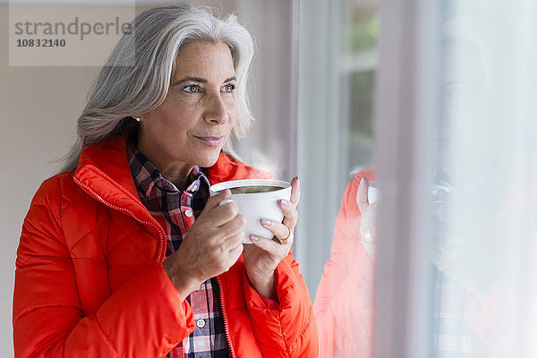 Kaukasische Frau trinkt Kaffee im Fenster