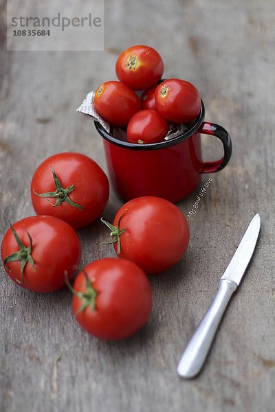 Tomaten mit Messer auf Holzuntergrund
