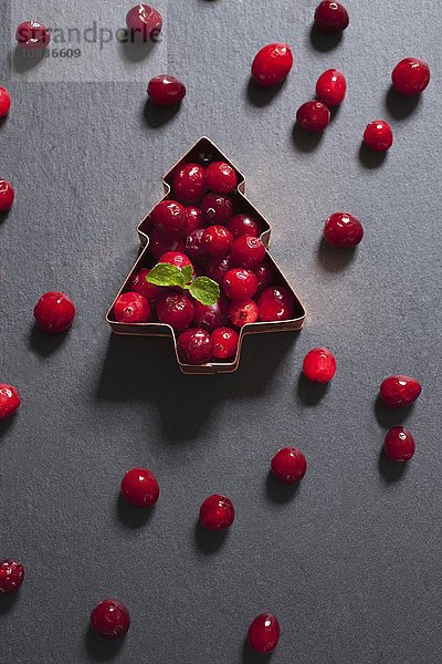 Tannenbaumförmiger Plätzchenausstecher gefüllt mit frischen Cranberries