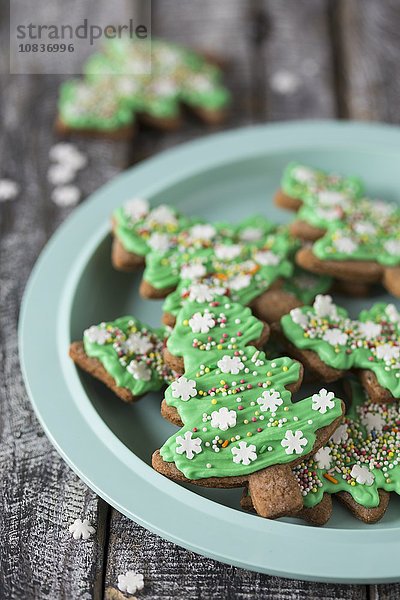 Lebkuchen-Weihnachtsbaum-Cookies mit grüner Zuckerglasur auf Teller