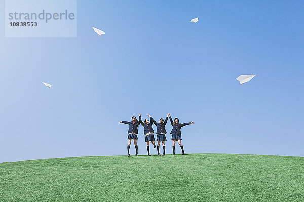 Japanische Oberschüler fliegen Papierflugzeuge in einem Stadtpark