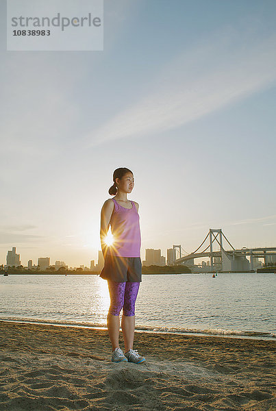 Junge Japanerin beim Dehnen vor ihrem Lauf in der Innenstadt von Tokio