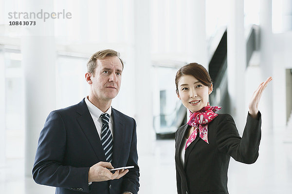 Eine attraktive japanische Flugbegleiterin hilft einem Kunden am Flughafen