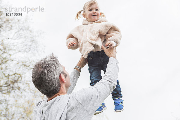 Vater hebt Kleinkind Tochter über Kopf