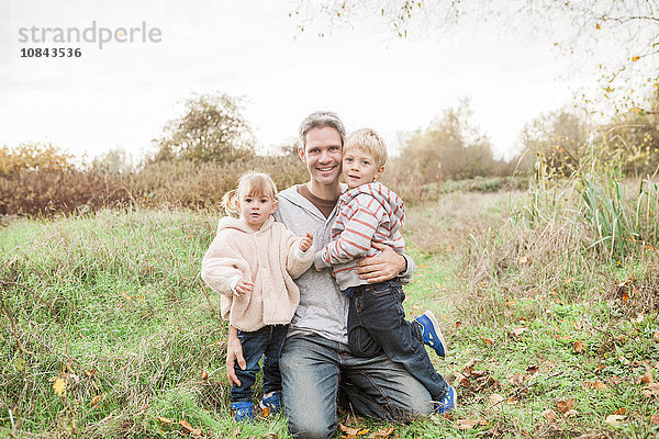 Portrait lächelnder Vater und Kleinkinder im Herbstpark