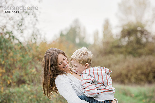 Mutter und Kleinkind lachend im Herbstpark
