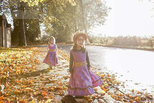Kleinkindermädchen in Halloween-Kostümen gehen im Herbstlaub