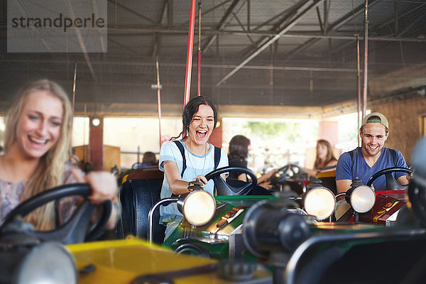 Enthusiastische Freunde  die im Vergnügungspark Stoßstangen fahren