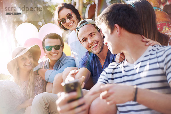 Lächelnde Freunde texten mit dem Handy im Vergnügungspark