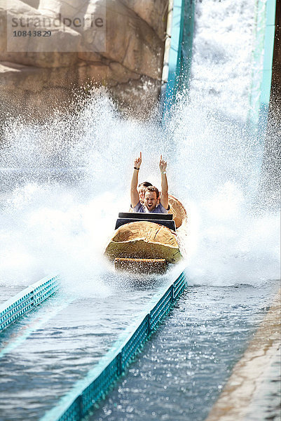 Enthusiastischer junger Mann reitet auf dem Wasserstamm im Vergnügungspark