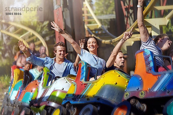 Begeisterte Freunde beim Jubeln auf der Achterbahn im Freizeitpark