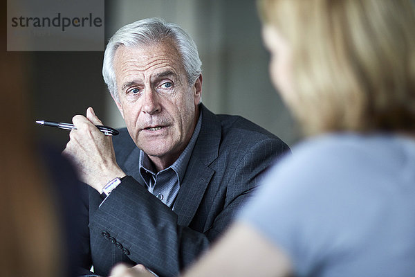 Senior Geschäftsmann hört der Geschäftsfrau beim Treffen zu.