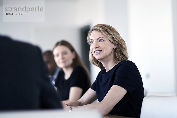Lächelnde Geschäftsfrau beim Zuhören im Meeting